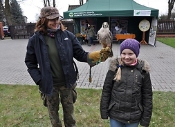 Powiększ zdjęcie. Przedstawicielka zespołu parków prezentuje dziewczynce ptaka podczas Dnia Ziemi w Łochowie