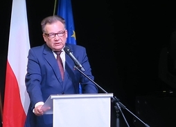 Przemawiający Adam Struzik przy pulpicie. Za nim flaga Polski i Unii Europejskiej
