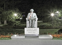 Pomnik marmurowy siedzącego premiera w ciemnym parku