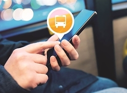 osoba trzyma w dłoniach smartfon na ekranie któego widać ikonę autobusu
