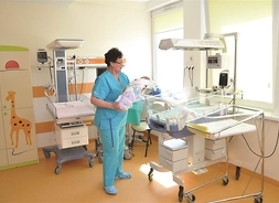 pielęgniarka trzyma niemowlę w odnowionej sali szpitalnej