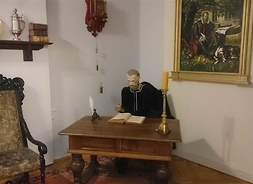 przy biurku siedząca figura z wosku przedstawiająca Jana Kochanowskiego