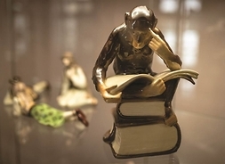 Ceramiczna figura zamyślonej małpki siedzącej na książkach