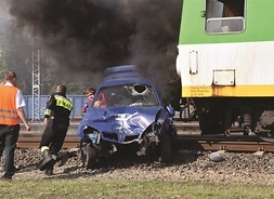 Wrak samochodu pod kołami pociągu. W środku kierowca upozorowany na rannego, biegną do niego strażacy