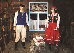 w centrum chałupy leży lalka dzieciątka, obok stoją manekiny mężczyzny i kobiety w ludowych strojach