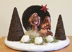 żłobek z kawy, przy nim dwa drzewa, a w środku figury Świętej Rodziny i owieczek