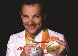 uśmiechnięty sportowiec pokazuje medale