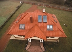 dom jednorodzinny z zainstalowanymi solarami na dachu - zdjęcie z lotu ptaka