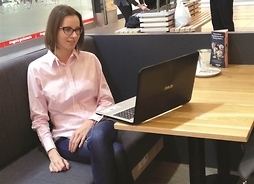 Młoda kobieta siedząca przed otwartym komputerem