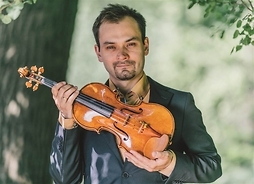 Skrzypek Janusz Wawrowski trzymający skrzypce, zdjęcie w plenerze