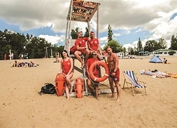 Grupa ratowników WOPR pozuje przy wieży obserwacyjnej na plaży