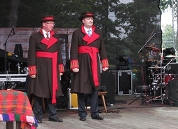 Zdjęcie przedstawia wicemarszałka Wiesława Raboszuka w stroju kurpiowskim stojącego na scenie w towarzystwie mężczyzny w takim samym ubraniu