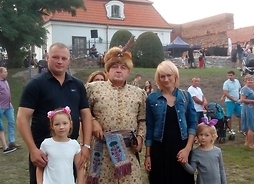 Radny Maciej Górski wraz z rodziną i mężczyzną w stroju szlachcica. Zdjęcie w plenerze