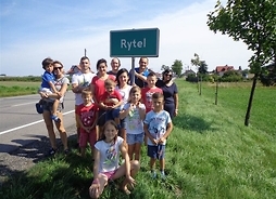 Zdjęcie przedstawia rodzinę Konrada Rytla stojącą przy tablicy z nazwą miejscowości Rytel