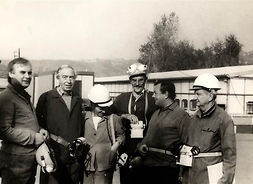 Zdjęcie archiwalne. Grupa osób, część z nich w budowlanych kaskach, pozuje do zdjęcia