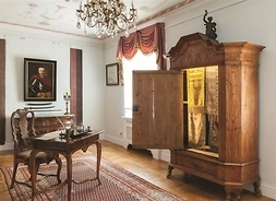 wnętrze muzeum, widok na szafę i stolik z krzesłem
