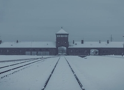na pierwszym planie tory kolejowe prowadzące do bramy wjazdowej do KL Auschwitz
