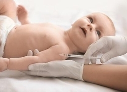 noworodek w pieluszce leży pielęgniarka robi mu zastrzyk w ramię