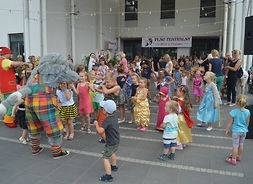 na tarasie tańczą dzieci i aktorzy przebrani w stroje postaci z bajek