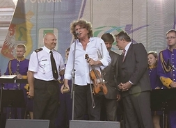 Ryszard Nowaczewski ze Zbigniewem Wodeckim, na scenie po koncercie, stoją obok siebie pozując do zdjęcia, za nimi kilku innych uczestników wydarzenia.