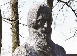 pomnik z kamienia przedstawia mężczyznę, umiejscowiona wśród drzew