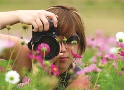 zdjęcie kwiatom na łące robi dziewczyna