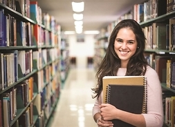 dziewczyna pozuje do zdjęcia w bibliotece, trzyma w ręku książki