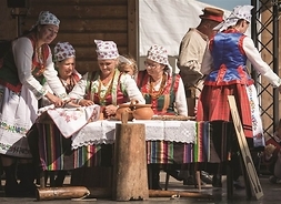 Grupa kobiet w strojach tradycyjnych prezentująca na scenie regionalne zwyczaje.