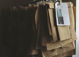 Papierowe wykroje ubrań wiszące w szeregu na wieszakach
