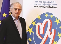 starszy mężczyzna pozuje do zdjęcia dla tle roll-upu z logo Fundacji My Obywatele UE