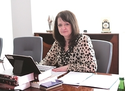 Janina Ewa Orzełowska przy biurku z tabletem