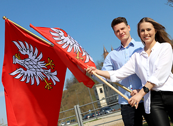 kobieta i mężczyzna trzymają w ręku dwie flagi województwa mazowieckiego