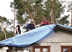Ludzie pomagający zabezpieczyć uszkodzony dach