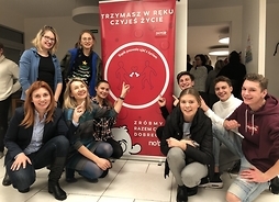 Grupa młodzieży przy banerze z nazwą  „Szpik pozwala ujść z życiem”