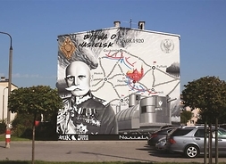 historyczny mural na tle budynku przedstawia mapę, dowódcę oraz eleenty zbrojenia