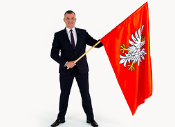 mężczyzna trzyma w dłoniach flagę województwa mazowieckiego