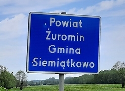 Droga, a przy niej tabliczka z napisem Powiat Żuromin Gmina Siemiątkowo