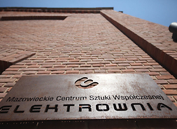 Tablica z logo Mazowieckiego Centrum Sztuki Współczesnej „Elektrownia” na ścianie głównego budynku