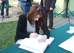 wicemarszłek Ewa Orzełowska składa podpis w księdze pamiątkowej