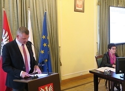 Przy mównicy stoi członek Zarządu Województwa Mazowieckiego Rafał Rajkowski.