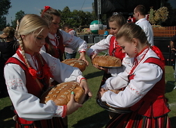Dzięwczęta ubrane w regionalne stroje dzielą się chlebem