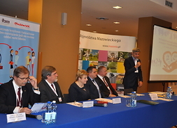 spotkanie otwiera Waldemar Patkowski, przy stole siedzą przedstawiciele organizatorów