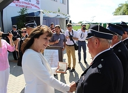 Janina Ewa Orzełowska poprzez uścisk ręki gratuluje i wręcza odznaczenie prezesowi OSP Zabruzdy