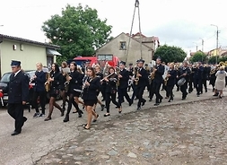 Strażacy maszerujący ulicą w Drobinie z instrumentami