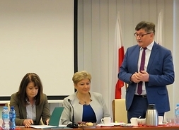przemawia Bogdan Ruszkowski, siedzą przy stole Elżbieta Lanc i Janina Ewa Orzełowska