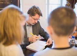 Pisarz składający podpis na książce, przed nim kolejka czekających dzieci