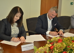 Przy stole wicemarszałek Janina Ewa Orzełowska i członek zarządu Rafał Rajkowski podpisują umowę