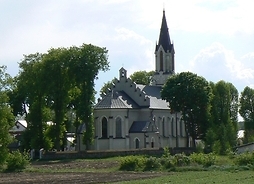 Murowany kościół z jedną strzelistą wieżą widziany od tyłu, z pola