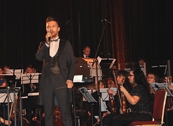 na scenie widoczni muzycy z orkiestry na czele z dyrygentem Adamem Sztabą