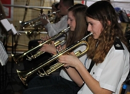 Zdjęcie przedstawia uczniów z Młodzieżowej Orkiestry Dętej. Członkowie grają na trąbkach